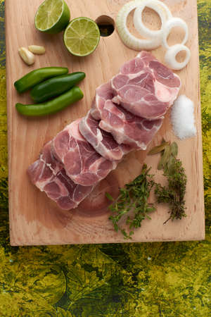 Pork for tacos, knuckle, around there are serrano peppers, garlic, onion, oregano, thyme and bay leaves, lemon, placed on a wooden base.の写真素材