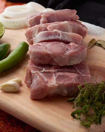 Pork for tacos, knuckle, around there are serrano peppers, garlic, onion, oregano, thyme and bay leaves, lemon, placed on a wooden base.の写真素材