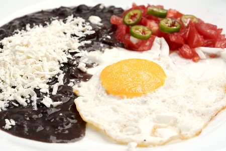 Fried egg accompanied with tomato and sliced jalapeÃ±o pepper, beans with grated cheeseの写真素材