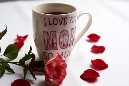 Cup of Americano type coffee, with the legend on the cup "I love you very much mom", adorned with a rose and petals aroundの写真素材
