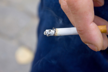Cigarette in hands, smoke from a cigarette, close upの写真素材