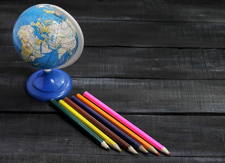 Color pencils and globe on a wooden background with space for text.の写真素材