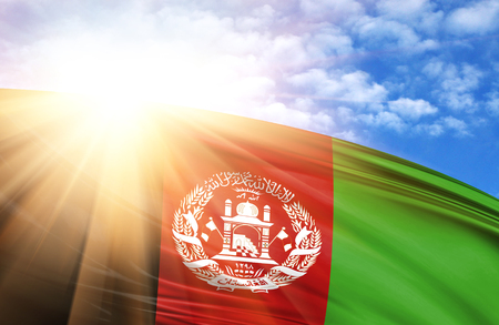 flag of Afghanistan against the blue sky with sun rays.の写真素材