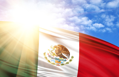 flag of Mexico against the blue sky with sun rays.の写真素材