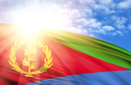 flag of Eritrea against the blue sky with sun rays.の写真素材