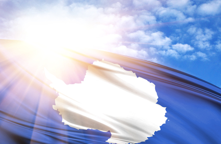 flag of Antarctic against the blue sky with sun rays.の写真素材