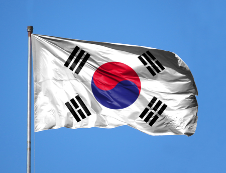 National flag of South Korea on a flagpole in front of blue sky.