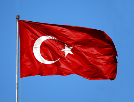 National flag of Turkey on a flagpole in front of blue sky.の写真素材