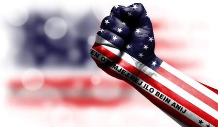 Flag of Bikini Atoll drawn on male fist, strength,power,concept of conflict. On a blurred background with a good place for your text.の写真素材