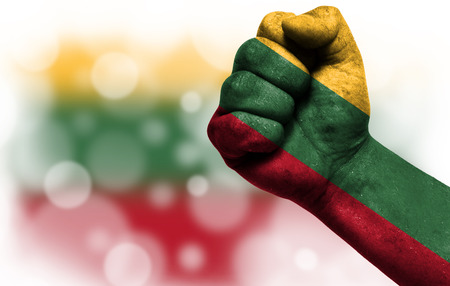 Flag of Lithuania painted on male fist, strength,power,concept of conflict. On a blurred background with a good place for your text.の写真素材