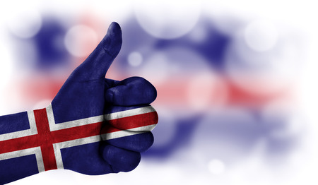 Flag of Iceland drawn on a man's hand with a thumb up, on a blurry background with a good place for textの写真素材