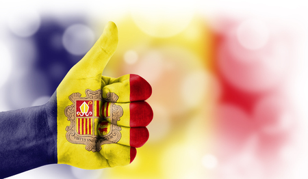 Flag of Andorra drawn on a man's hand with a thumb up, on a blurry background with a good place for textの写真素材