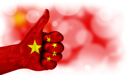 Flag of China drawn on a man's hand with a thumb up, on a blurry background with a good place for textの写真素材