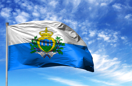 National flag of San marino on a flagpole in front of blue sky.の写真素材