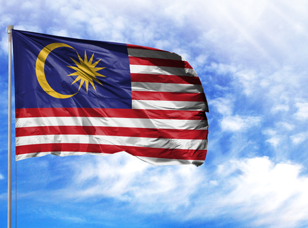 National flag of Malasia on a flagpole in front of blue sky.の写真素材
