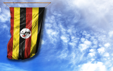 Flag of Uganda. Vertical flag, against blue sky with place for your textの写真素材