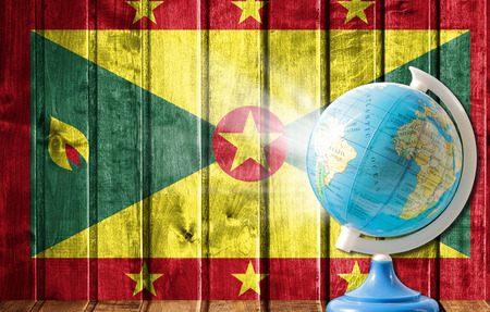Globe with a world map on a wooden background with the image of the flag of Grenada. The concept of travel and leisure abroad.の写真素材