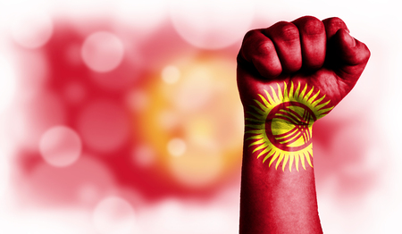 Flag of Kyrgyzstan painted on male fist, strength,power,concept of conflict. On a blurred background with a good place for your text.の写真素材