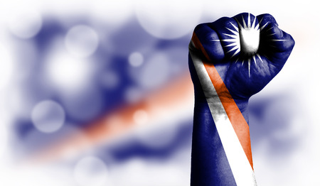Flag of Marshall Islands painted on male fist, strength,power,concept of conflict. On a blurred background with a good place for your text.の写真素材