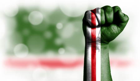 Flag of Chechen Republic of Ichkeria painted on male fist, strength,power,concept of conflict. On a blurred background with a good place for your text.の写真素材