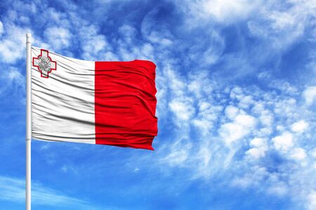 National flag of malta on a flagpole in front of blue skyの写真素材