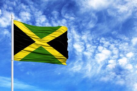 National flag of Jamaica on a flagpole in front of blue skyの写真素材