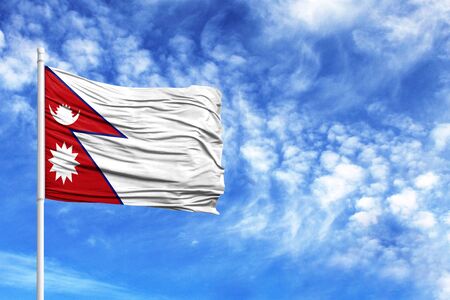 National flag of Nepal on a flagpole in front of blue skyの写真素材