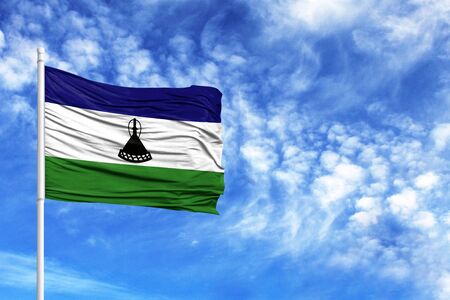 National flag of Lesotho on a flagpole in front of blue skyの写真素材