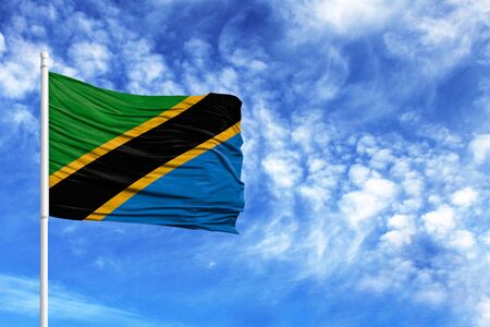 National flag of Tanzania on a flagpole in front of blue skyの写真素材