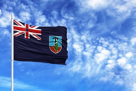 National flag of Montserrat on a flagpole in front of blue skyの写真素材