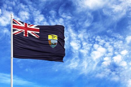 National flag of Saint Helena on a flagpole in front of blue skyの写真素材