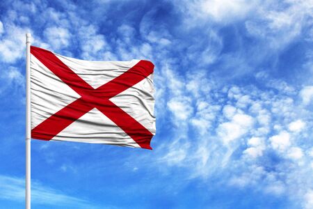 National flag State of Alabama on a flagpole in front of blue skyの写真素材