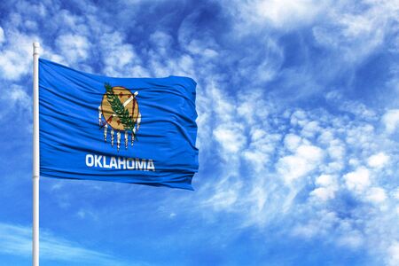 National flag State of Oklahoma on a flagpole in front of blue skyの写真素材