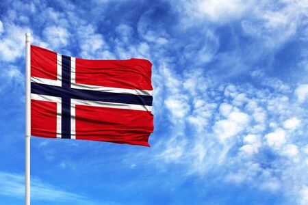 National flag of Norway on a flagpole in front of blue skyの写真素材