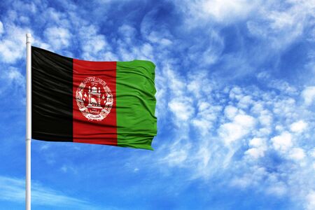 National flag of Afghanistan on a flagpole in front of blue skyの写真素材