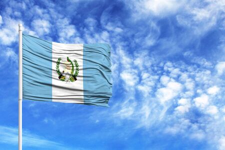 National flag of Guatemala on a flagpole in front of blue skyの写真素材