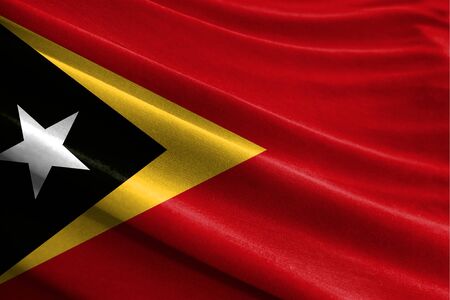 Realistic flag of East Timor on the wavy surface of fabricの写真素材