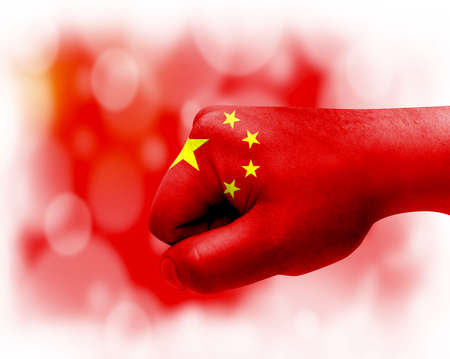 Flag of China painted on male fist, strength, power, concept of conflict. On a blurred background.の写真素材