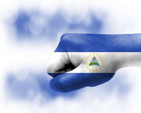 Flag of Nicaragua painted on male fist, strength, power, concept of conflict. On a blurred background.の写真素材