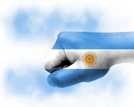Flag of Argentina painted on male fist, strength, power, concept of conflict. On a blurred background.の写真素材