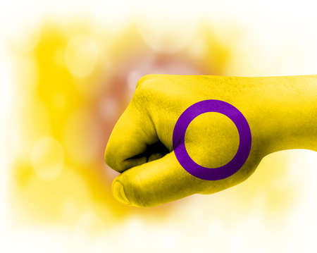 Flag of intersex pride painted on male fist, strength, power, concept of conflict. On a blurred background.の写真素材
