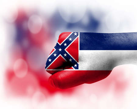 Flag of State of Mississippi painted on male fist, strength, power, concept of conflict. On a blurred background.の写真素材
