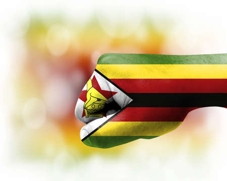 Flag of Zimbabwe painted on male fist, strength, power, concept of conflict. On a blurred background.の写真素材