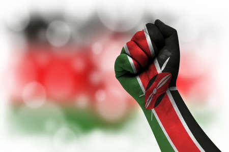 Flag of Kenya painted on male fist, strength, power, concept of conflict. On a blurred background.の写真素材