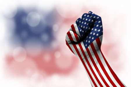 Flag of America painted on male fist, strength, power, concept of conflict. On a blurred background.の写真素材