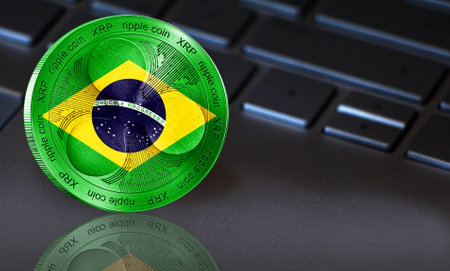 Coin Ripple (XRP) with the flag of Brazil depicted on it. In the background a keyboard with a good place for your text. New cryptocurrency, business concept.の写真素材