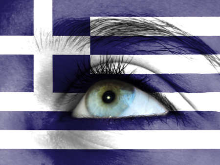 Close up view of a young girl. The flag of Greece is painted on the girl face.