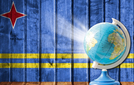 Globe with a world map on a wooden background with the image of the flag of Aruba. The concept of travel and leisure abroad.の写真素材