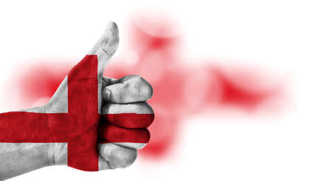 Flag of England drawn on a man's hand with a thumb up, on a blurry background with a good place for textの写真素材