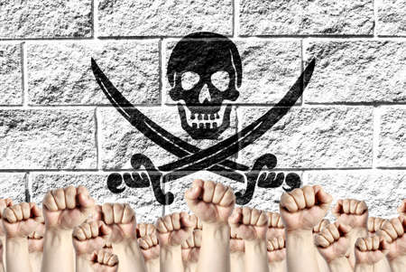 Raised fists against the background of the depicted flag of Pirates white on a brick wall, a concept of strength and unity.の写真素材